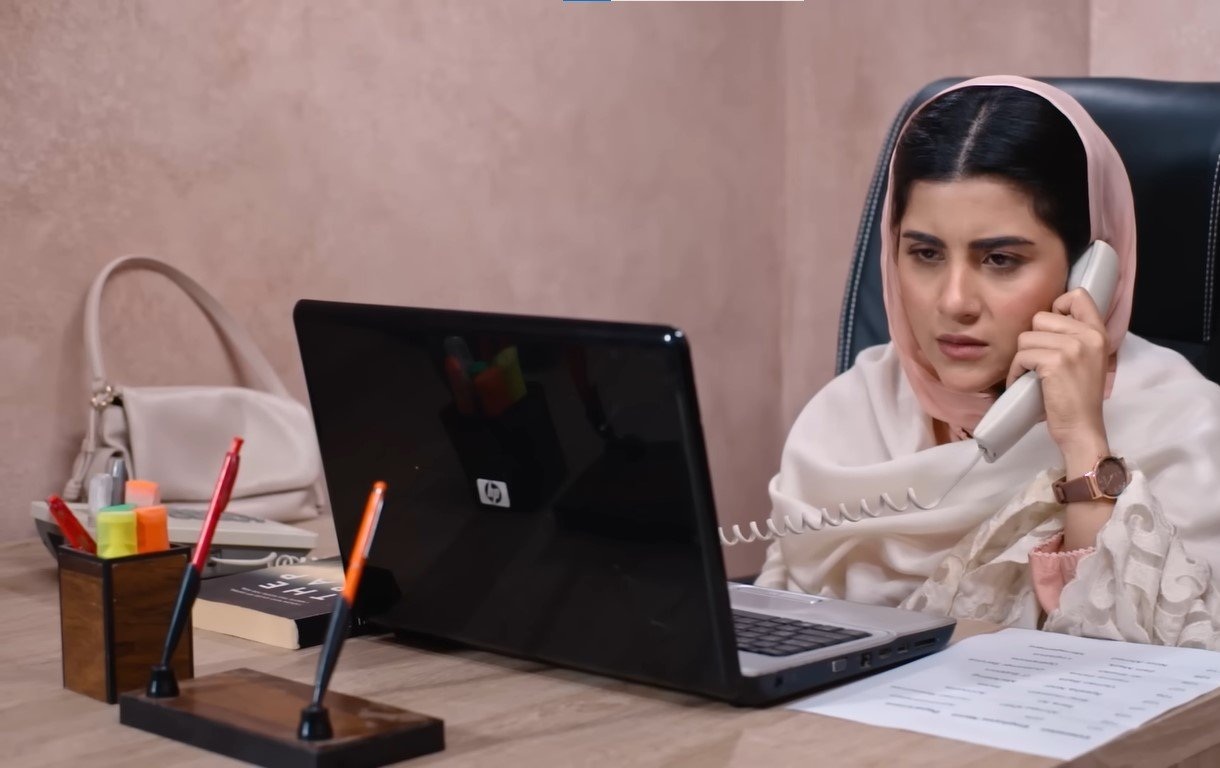 Shabana speaking on a telephone at a desk beside an open laptop