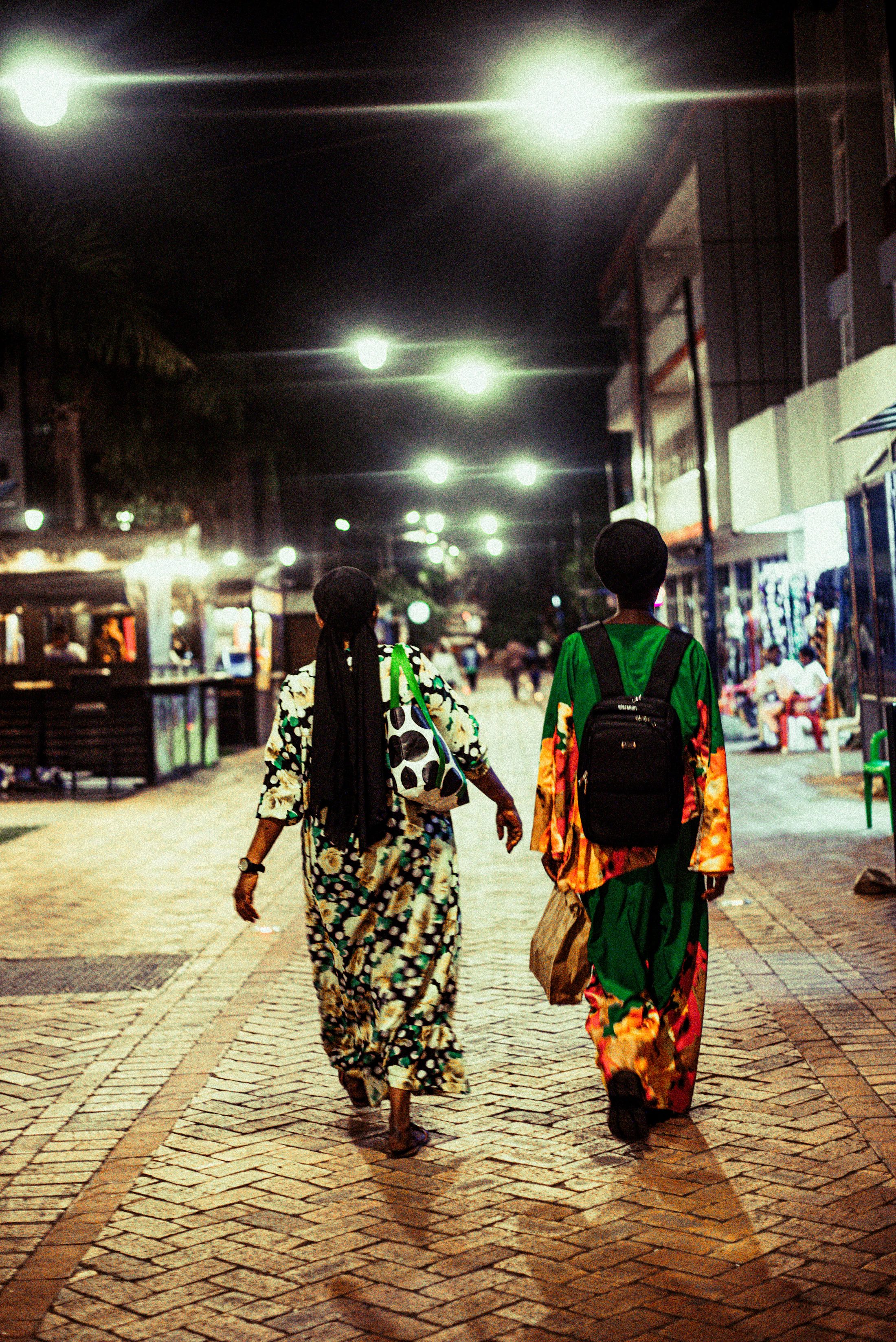 Two people taking an evening walk along a lit city street
